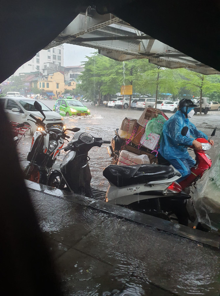Mưa lớn khiến các phương tiện xe máy phải dừng trú mưa.