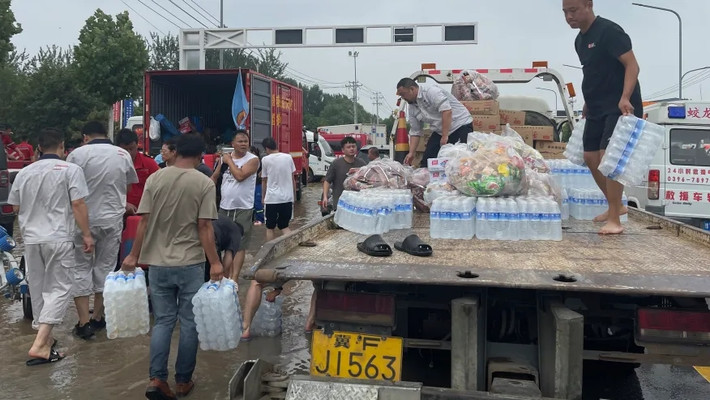 Người dân nhận đồ tiếp tế từ một chiếc xe tải để sơ tán khỏi lũ lụt ở Trác Châu. Ảnh: AP.