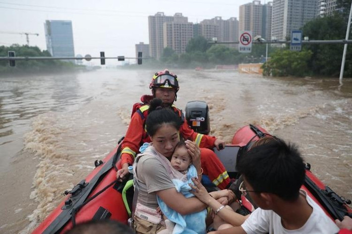 Nhân viên cứu hộ sơ tán người dân bị mắc kẹt trong nước lũ ở Trác Châu. Ảnh: Reuters.
