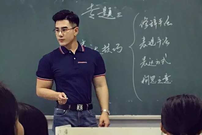 Thầy giáo trẻ mặc áo phông tôn lên vóc dáng khỏe khoắn và cơ bắp lực lưỡng khi đứng trên bục giảng.