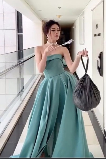 Cô mặc váy dạ hội, trang điểm lộng lẫy và catwalk dọc hành lang với túi đựng rác trên tay. Người hâm mộ tỏ ra thích thú với chi tiết Hoa hậu Hoàn vũ 2019 không biết thùng rác trong khu chung cư đặt ở đâu.