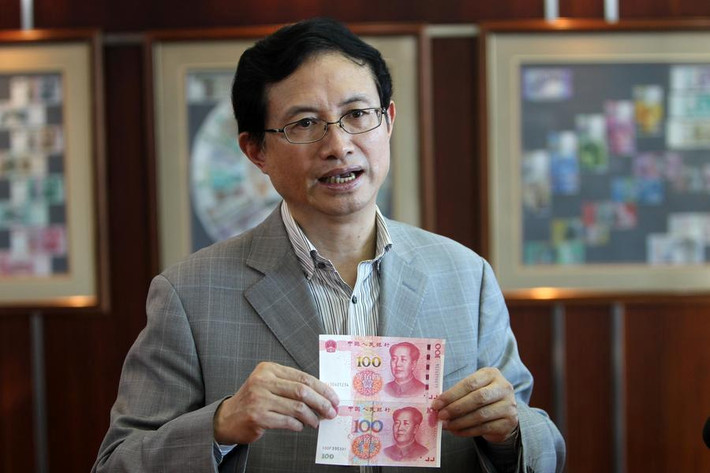 Ông Shao Guowei, Giám đốc công nghệ của công ty in ấn và đúc tiền Trung Quốc cầm tờ tiền giấy cũ so sánh với mẫu tiền mới.