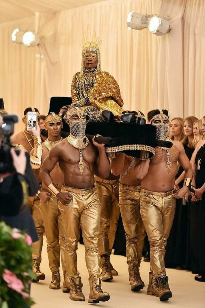 Hình ảnh trên khiến nhiều người nhớ đến màn xuất hiện của Billy Porter trên thảm đỏ Met Gala 2019 khi anh được cả một dàn các cận vệ trong trang phục màu vàng kim khênh trên một chiếc kiệu giường như một vị Pharaoh của Ai Cập cổ đại.