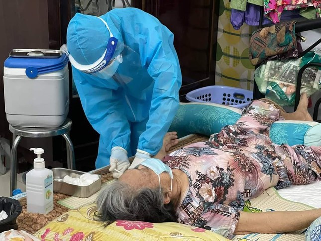 Sau đó nhân viên y tế dẽ tiêm cho một cụ bà mắc bệnh không ngồi dậy được.