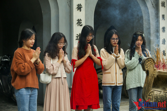Còn tại quận Cầu Giấy (Hà Nội), thời tiết nắng ấm cuối tuần lại gần với ngày lễ Tình nhân (14/2) nên nhiều bạn trẻ Hà Nội rủ nhau đến chùa Hà thắp hương, dâng lễ cầu duyên với mong muốn tìm được một nửa kia của mình. Trong ảnh là bạn Nguyễn Thị Trang Nhung (áo dài đỏ) cùng bạn bè tới chùa Hà cầu tình duyên, may mắn.