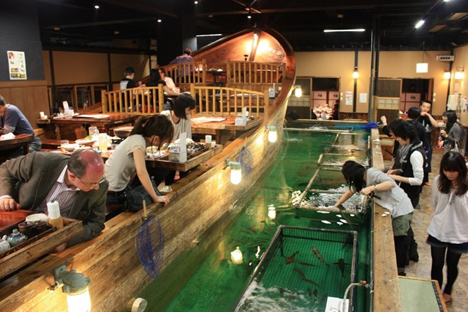 Tự tìm nguyên liệu cho bữa ăn: Ở nhà hàng Zauo, Tokyo, nếu muốn có đồ ăn, trước hết bạn phải tự bắt cá bằng cách sử dụng cần câu và vợt. Bạn không thể thả lại con đã bắt xuống bể. Mỗi khi cá cắn câu, nhân viên nhà hàng sẽ gõ trống ăn mừng. Bàn ăn được bày trên một thuyền gỗ lớn nhìn ra chỗ các thực khách đang câu cá. Ảnh: Blog.zingarate.com.
