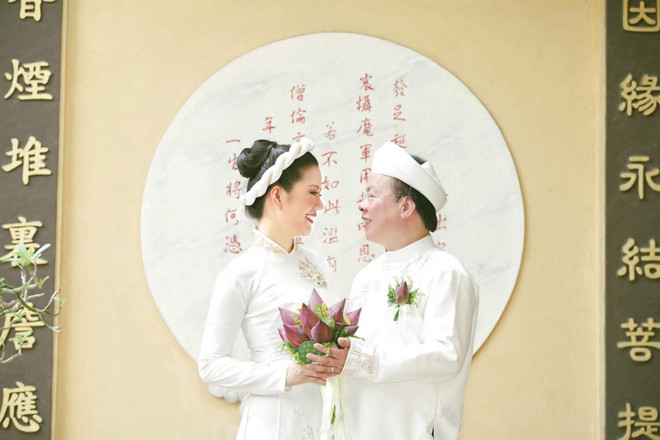 Hai vợ chồng cô đều chọn lựa trang phục truyền thống màu trắng. Chú rể cài hoa sen trên ngực và cả hai cùng đón nhận sự chúc phúc của bạn bè, người thân.