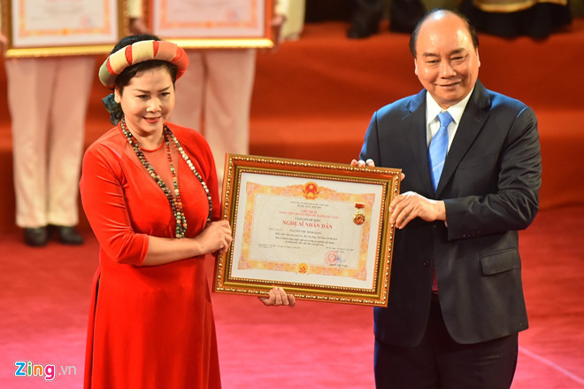 Nghệ sĩ Minh Hằng mặc áo dài đỏ, hạnh phúc khi được Thủ tướng Nguyễn Xuân Phúc trao tặng danh hiệu.