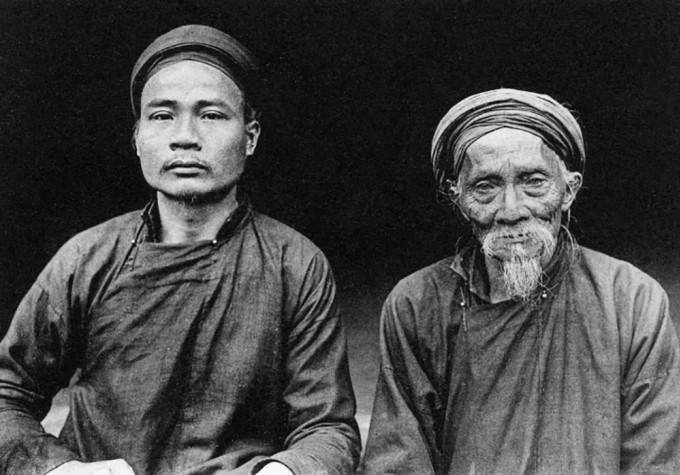 Bức ảnh chụp hai cha con ở miền Bắc Việt Nam trong trang phục áo dài cổ đứng và đội khăn đóng.