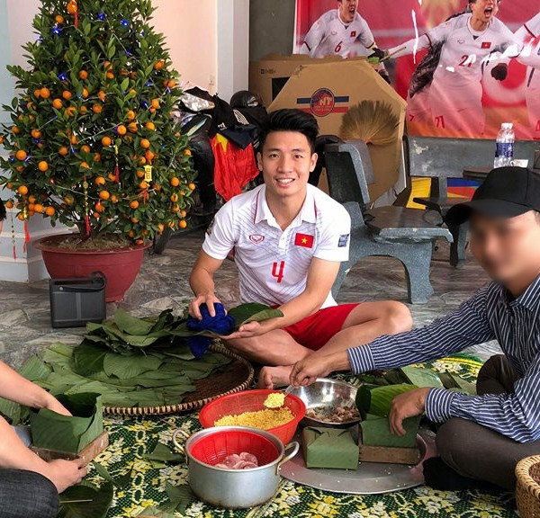 Trung vệ Bùi Tiến Dũng về nhà vẫn mặc quần đùi áo số ngồi gói bánh cùng gia đình.