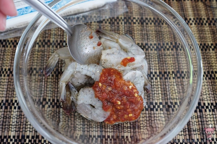 Cách làm chả giò cuộn tôm: Khứa nhẹ dưới bụng tôm để con tôm thẳng ra. Sau đó, ướp tôm với 2 muỗng canh tương ớt, 1 muỗng canh mật ong, muối, hạt tiêu rồi trộn đều cho ngấm.