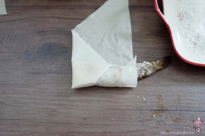 Trải miếng chả giò ra, cho tôm vào, cuộn lại, để phần đuôi tôm thò ra.