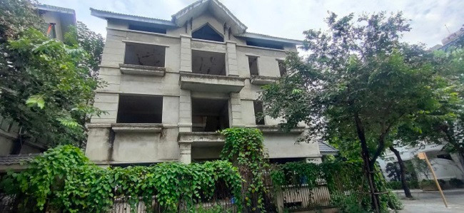 Cận cảnh một căn biệt thự chưa được hoàn thiện, cây leo mọc xung quanh lối ra vào.