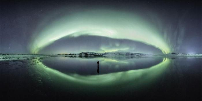 Cực quang thắp sáng bầu trời ở Iceland. Vòng xoáy ánh sáng này mô tả cực quang ở độ đẹp nhất. Bức ảnh bầu trời rực rỡ được phản chiếu hoàn hảo trên cửa sông bên dưới với hình ảnh một con người đơn độc đứng giữa khung hình, phản ánh vẻ đẹp rộng lớn của thế giới tự nhiên. Tác giả: Larryn Rae.