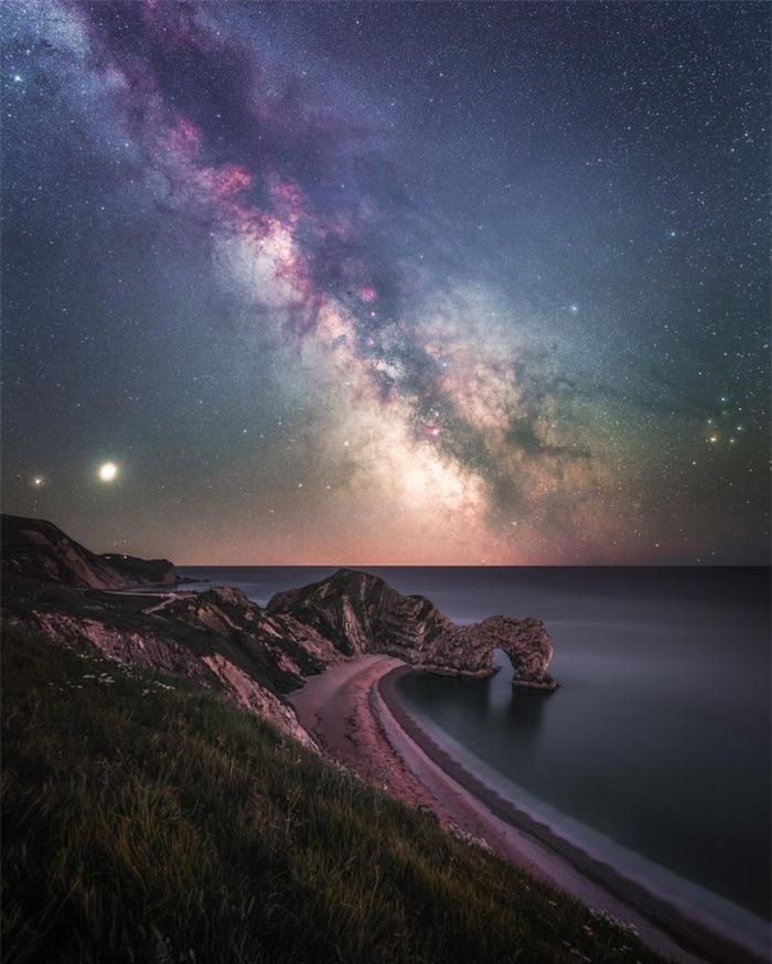 Bức ảnh dải ngân hà lấp lánh phía trên vòm đá vôi tự nhiên Durdle Door ở Lulworth, khu vực đường bờ biển nổi tiếng của Anh. Trong dải ngân hà, Sao Thổ và Sao Mộc ẩn nấp ở ngoại vi bên trái của bức ảnh. Tác giả: Anthony Sullivan. Danh sách rút gọn cho giải thưởng Nhiếp ảnh thiên văn của năm 2021 đã được Viện bảo tàng Hoàng gia Greenwich công bố. Giải thưởng hiện bước sang năm thứ 13, được coi là cuộc thi chụp ảnh thiên văn hàng đầu trên thế giới.