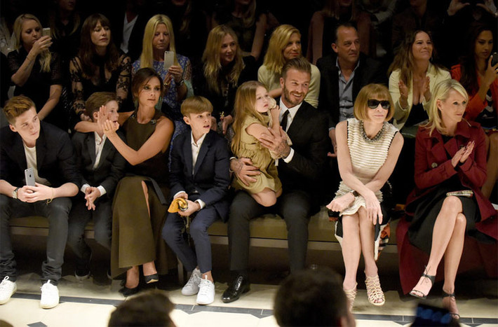 Gia đình David Beckham - Victoria tề tựu đông đủ tại hàng ghế đầu trong show diễn thời trang của Burberry hồi tháng 4/2015. Vic thì ôm chặt con trai Cruz còn Harper thì bám dính lấy bố Beck.