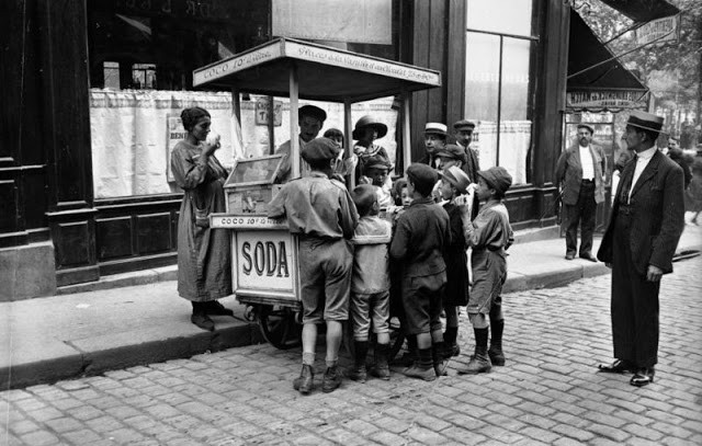 Những đứa trẻ thích thú ghé vào quán hàng rong bán kem, soda, kẹo trên đường phố Paris năm 1925.