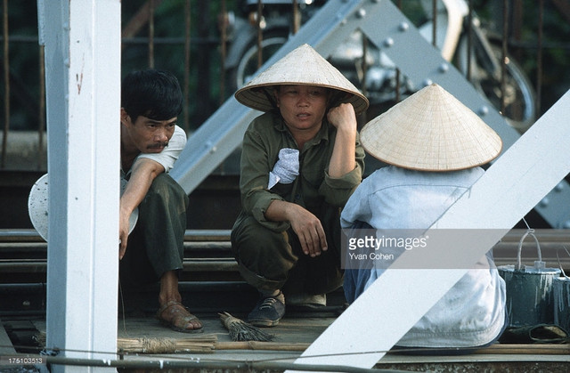 Một nhóm công nhân sửa cầu ngồi nghỉ ngơi, trò chuyện trong lúc giải lao.
