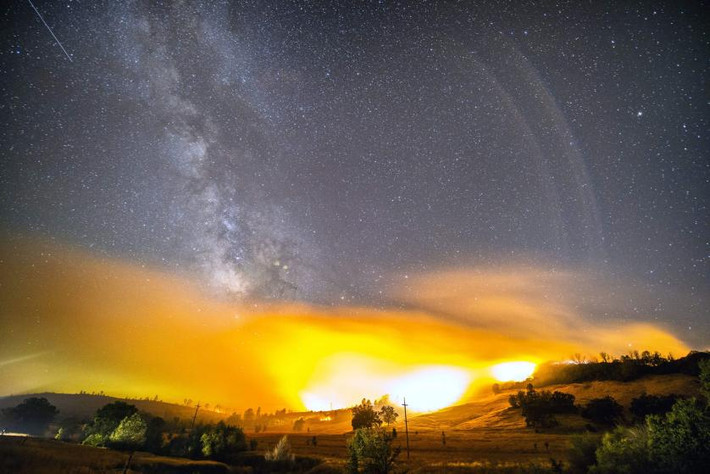 Một vệt sao băng tuyệt đẹp vụt ngang bầu trời trong trận mưa sao băng Perseid (mưa sao băng Anh Tiên). Bên dưới là ánh lửa rực sáng từ trận cháy rừng gần Clearlake, California. Ảnh chụp vào ngày 12/8/2015.