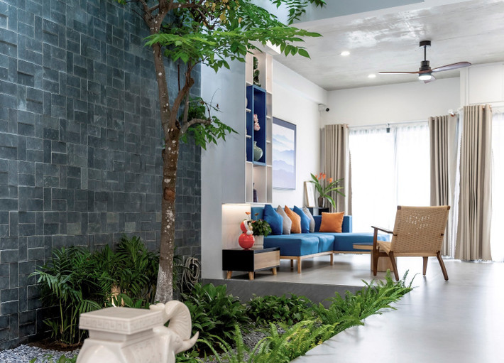 Vào bên trong, một khoảng sân vườn hơn 10 m2 được bố trí ở trung tâm tầng trệt có vai trò như một không gian cảnh quan đặc sắc, kết nối với phòng khách phía trước và khu vực phòng ăn và bếp phía sau.