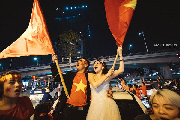 Hòa vào dòng người đổ ra đường với nồi niêu, xoong chảo, kèn, trống, cờ hoa... để cổ vũ cho chiến tích lịch sử của đội tuyển U23 Việt Nam, là một cặp đôi cô dâu - chú rể Hà thành gây sốt với bộ ảnh cưới "không thể độc hơn".