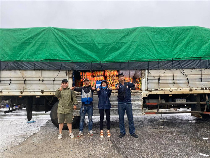Hòa Minzy mặc áo mưa cùng anh em chuyển một xe container áo phao đến cứu trợ.