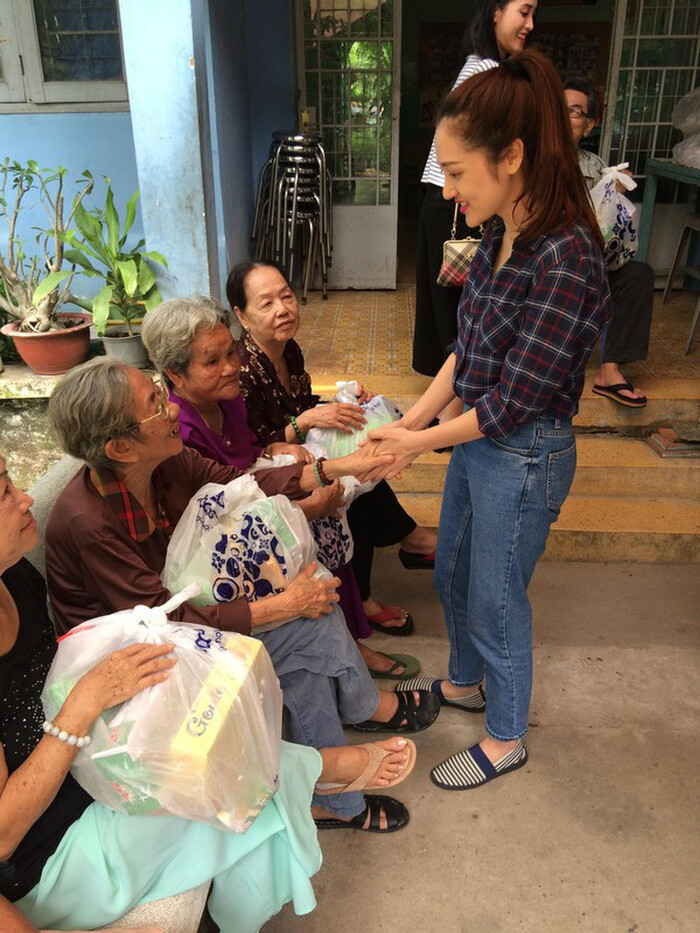 Bảo Anh diện áo sơ mi kẻ, quần jeans và giày lười thể thao tạo nên sự trẻ trung vừa phải, gần gũi và thân thiện khi đi từ thiện.