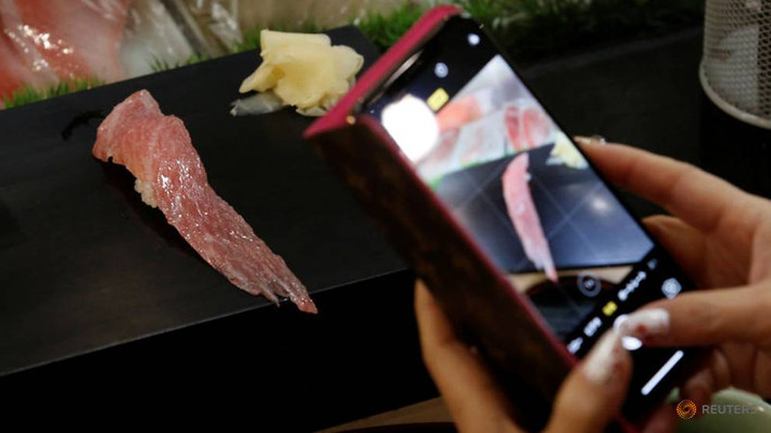 Một khách hàng chụp ảnh một miếng sushi cá ngừ được làm thịt từ con cá ngừ có giá kỷ lục.