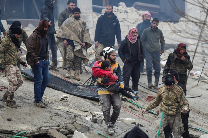 Nhân viên cứu hộ bế đứa trẻ khỏi đống đổ nát ở Syria. Ảnh: Reuters.