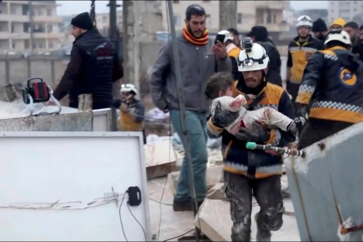 Một nhân viên cứu hộ bế đứa trẻ bị thương ra khỏi đống đổ nát ở Syria. Ảnh: Reuters.