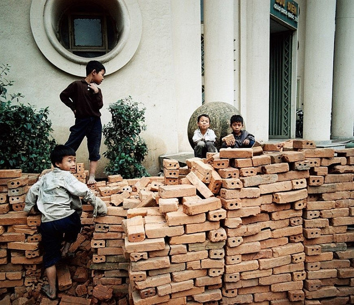Một nhóm trẻ em chơi đùa cạnh một đống gạch.