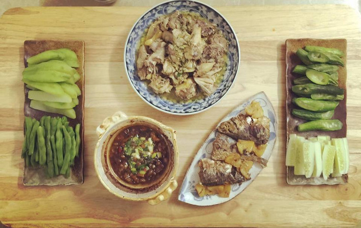 Đây là một mâm cơm truyền thống Việt Nam với rau củ luộc chấm kho quẹt, cá biển tươi kho dứa và thịt gà rang gừng.