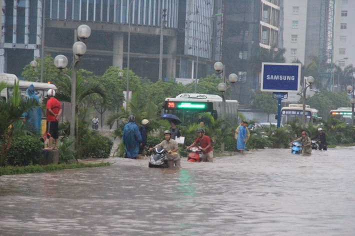 Những trận mưa lớn gây ra lượng nước cao bất thường trong một ngày hoặc một giờ, làm tăng khả năng lũ lụt. Tất nhiên, lượng mưa lớn không gây ra lũ lụt, mà chủ yếu nó phụ thuộc vào địa hình và cơ sở hạ tầng của thành phố. Ảnh lụt lội tại đường Dương Đình Nghệ, Hà Nội. Nguồn ảnh: Kiến Thức.
