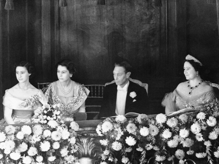 Năm 1950: Nữ hoàng Anh Elizabeth II là một công chúa trẻ tuổi đang ngồi kế bên ngai vàng của cha mình, vua George VI. Ảnh các thành viên của gia đình hoàng gia Anh từ trái sang phải: Công chúa Margaret, Công chúa Elizabeth, Vua George VI, Nữ hoàng Elizabeth I.