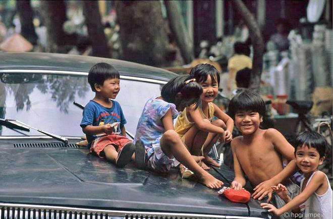 Một nhóm trẻ em vui đùa trước capo ô tô và thích thú khi được chụp ảnh.