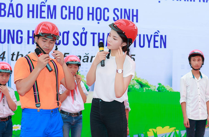 Cô cùng nghệ sĩ Xuân Bắc hướng dẫn cách đội mũ bảo hiểm đúng cách cho các em học sinh.