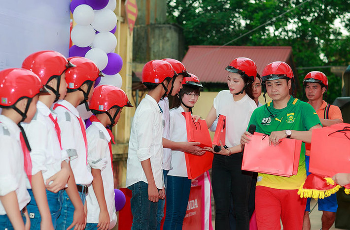 Cô cùng nghệ sĩ Tự Long, Xuân Bắc, trao những phần quà nhỏ cho các em học sinh.