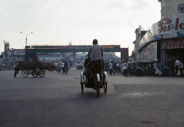 Người lái xích lô chở đầy hàng hóa trên đường phố Sài Gòn.