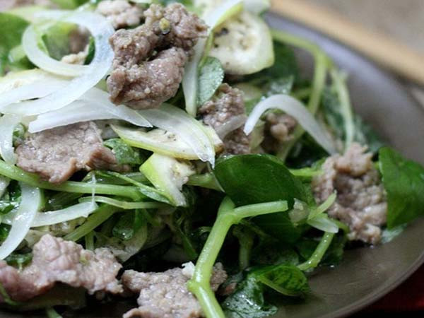 Thịt bò rửa sạch thái mỏng, ướp ít tỏi băm, hạt nêm và dầu ăn cho thấm. Rau càng cua bỏ lá sâu, rửa sạch, ngâm nước muối loãng, vẩy ráo, cho vào thố lớn. Hành tây bóc vỏ, xắt khoanh, cho vào hỗn hợp dầu giấm. Cà chua bi xắt lát. Phi tỏi, cho thịt bò vào thố rau, chan nước dầu giấm, hành tây và cà chua bi vào cùng.
