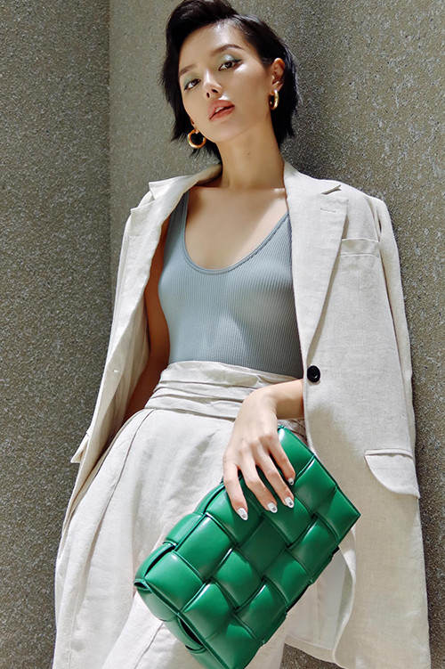 Khánh Linh The Face diện suit màu trắng phối thêm clutch da đan màu xanh lá để tạo điểm nhấn cho set đồ.