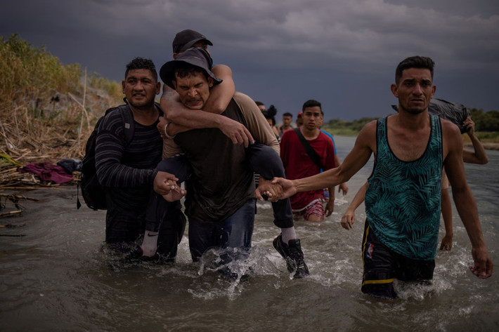 Một người đàn ông cõng người em họ bị tật nguyền lội qua sông Rio Grande. Ảnh: Reuters.