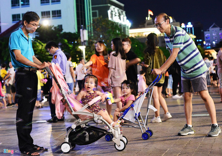 Nhiều trẻ em được người lớn dẫn đi bằng xe đẩy, thỏa thích vui chơi giữa phố đông người.
