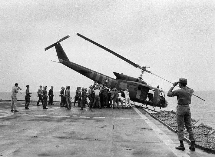 Nhân viên trên tàu USS Blue Ridge cùng nhau hợp sức đẩy một trực thăng xuống biển để có thêm chỗ cho những người rời khỏi Sài Gòn trước khi chiến tranh kết thúc. Ảnh: AP.