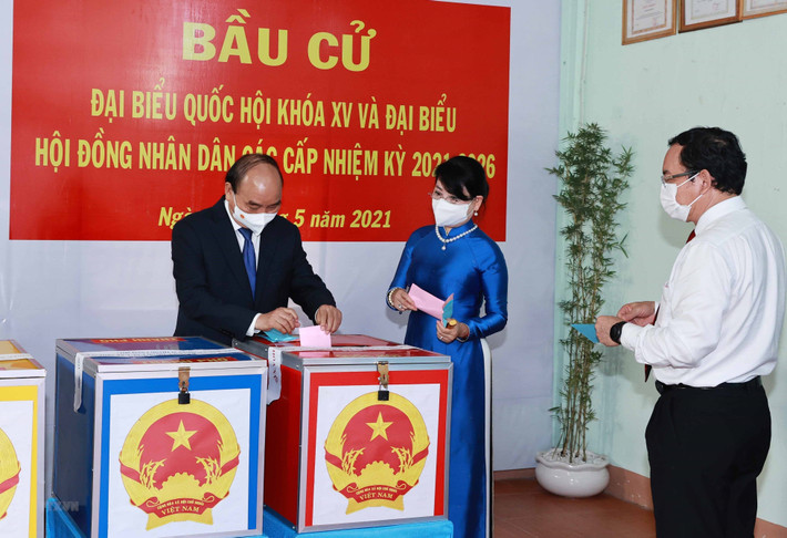 Chủ tịch nước Nguyễn Xuân Phúc cùng Phu nhân và Bí thư Thành uỷ Thành phố Hồ Chí Minh Nguyễn Văn Nên cùng các cử tri bỏ phiếu bầu đại biểu Quốc hội khóa XV và Hội đồng nhân dân các cấp nhiệm kỳ 2021-2026. (Ảnh: Thống Nhất/TTXVN)