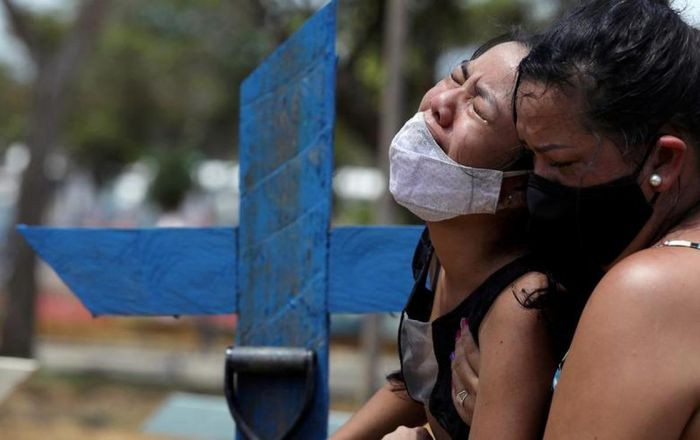 Kelvia Andrea Goncalves, 16 tuổi, được người dì đỡ lấy khi cô khóc nức nở và không thể đứng vững trong đám tang của mẹ. Mẹ của Kelvia 39 tuổi tử vong vì nhiễm COVID-19. Bà được chôn cất tại nghĩa trang Parque Taruma, Manaus, Brazil ngày 17/1/2021.