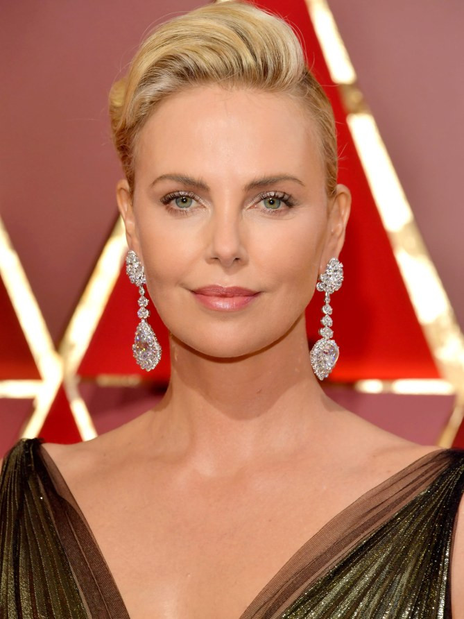 Charlize Theron khoe sắc trên thảm đỏ Oscar với đôi hoa tai kim cương nặng 25 carat hình quả lê cùng chiếc đồng hồ chopard đính kim cương nặng 26 carat, hai chiếc nhẫn kim cương to tướng đeo trên ngón tay. (Ảnh: WireImage)