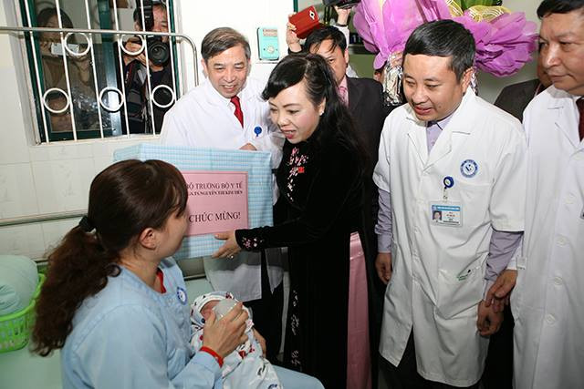 Hình ảnh Bộ trưởng Nguyễn Thị Kim Tiến thăm và tặng quà cho gia đình cháu bé đầu tiên chào đời nhờ phương pháp mang thai hộ.