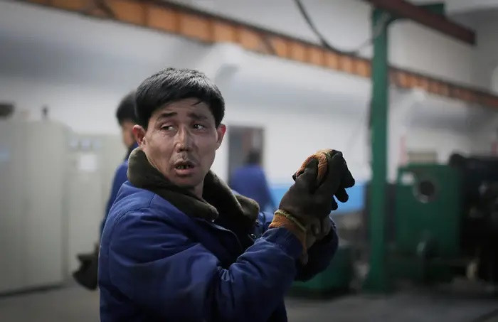 Một công nhân nhà máy cởi găng tay tại Nhà máy dây điện Bình Nhưỡng 326 ở Bình Nhưỡng, Triều Tiên. Ảnh: AP.