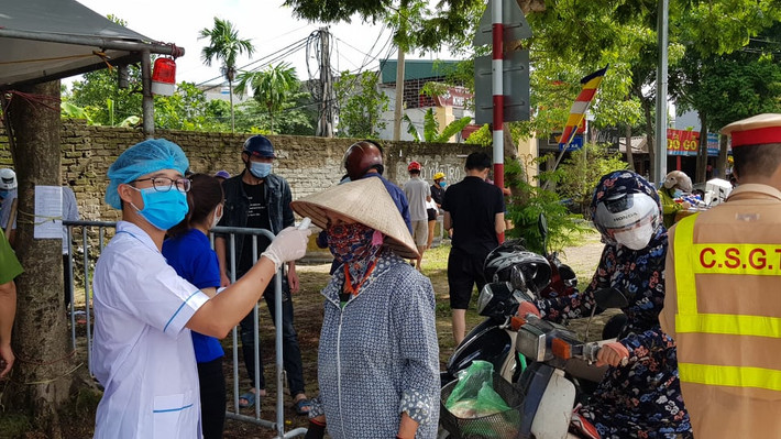 Nhân viên y tế kiểm tra thân nhiệt người dân qua chốt.