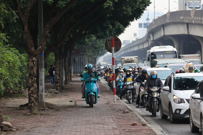 Lòng đường chật kín xe buộc những phương tiện xe máy phải leo lên vỉa hè để di chuyển.